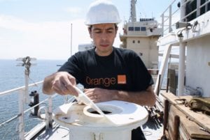 Orange engineer installs network equipment on board.